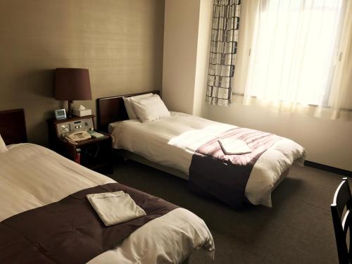 a hotel room with two beds and a window at Hotel Tomakomai Green Hills in Tomakomai