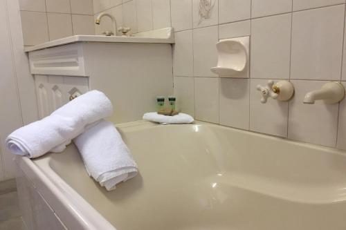 a white bathroom with towels on the side of a tub at The Ledge Holiday House in Halls Gap