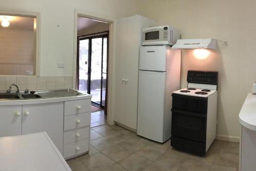 a kitchen with a white refrigerator and a microwave at The Ledge Holiday House in Halls Gap