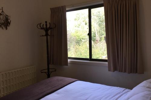 een slaapkamer met een bed en een groot raam bij The Ledge Holiday House in Halls Gap