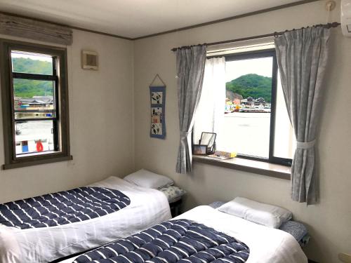 two beds in a room with a window at Guest House Seaside Namihei in Naoshima