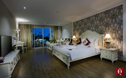 een slaapkamer met een groot wit bed en een televisie bij Silk Queen Grand Hotel in Hanoi