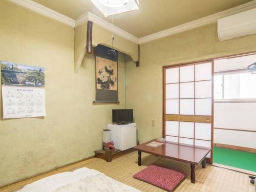 a room with a table and a tv in it at Kenrokuen in Nobeoka