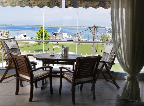 einen Tisch und Stühle auf einem Balkon mit Blick auf das Wasser in der Unterkunft Konstantinos Luxury Apartment in Keramotí