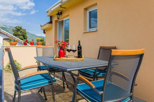 a table and chairs on a patio with a bottle of wine at Holiday Home Mirela in Orebić
