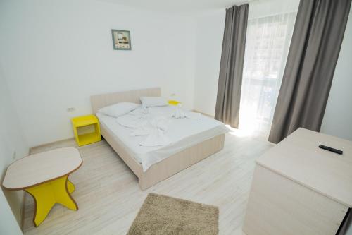 1 dormitorio con cama blanca y taburete amarillo en Glam Boutique Hotel, en Eforie Nord