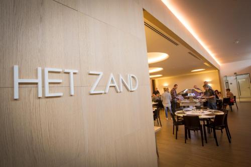 a sign on the wall of a restaurant with tables at Let's Meet Elewijt in Elewijt