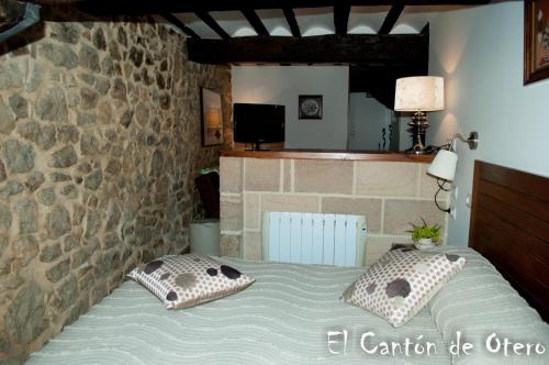a bedroom with a bed with pillows and a stone wall at Estudios El Canton de Otero in Santillana del Mar