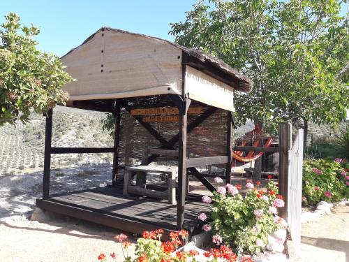 a small wooden shelter in a garden with flowers at La Choza De Mamuyo in Montefrío