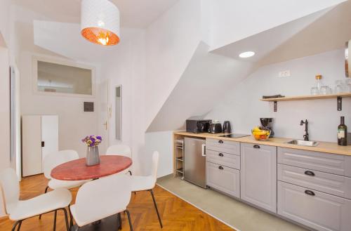 eine Küche mit einem kleinen Tisch und weißen Stühlen in der Unterkunft Apartment Dox in Dubrovnik