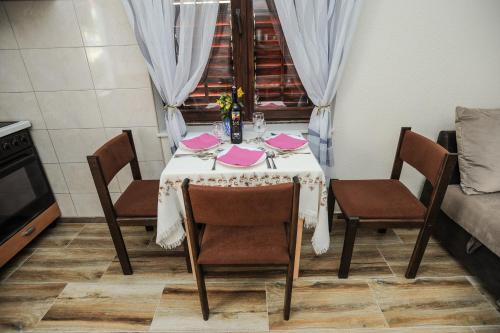 a dining room table with chairs and pink napkins at Apartments Phoenix in Ivanica