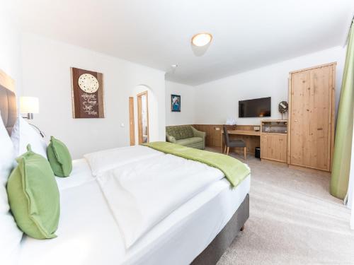 a bedroom with a large white bed and a desk at Vitalhotel Marienhof in Velden am Wörthersee