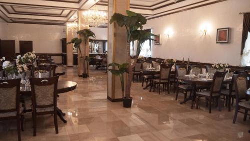 uma sala de jantar com mesas, cadeiras e flores em Hotel KREZ em Qyzylorda
