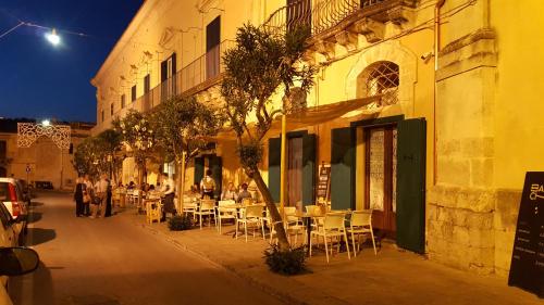 a group of people sitting at tables outside a building at Epoca - Camere con stile in Ragusa