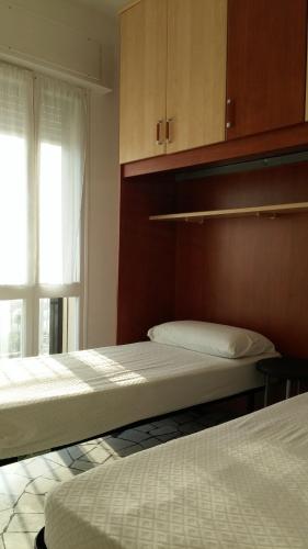 two beds in a room with a window at Alba Appartamenti in Sottomarina