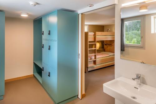 a bathroom with a blue cabinet next to a sink and a bunk bed at Crans-Montana Youth Hostel in Crans-Montana