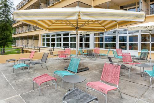 a patio area with chairs, tables and umbrellas at Crans-Montana Youth Hostel in Crans-Montana