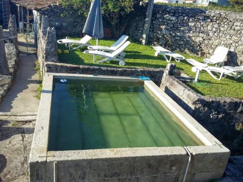 a swimming pool with two lawn chairs and an umbrella at Albergue Casa do Sardão in Carreço