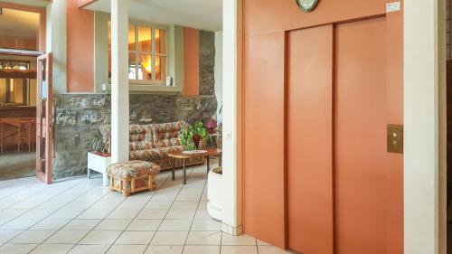 a lobby with an orange door and a couch at Hôtel les Berges in Chippis