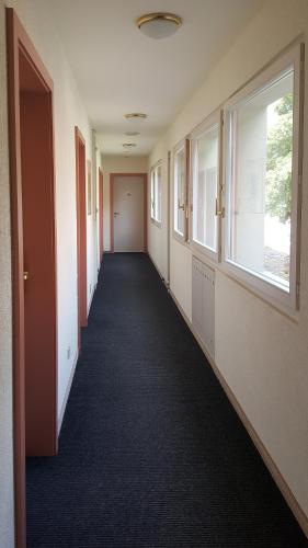 an empty hallway in an office building with windows at Hôtel les Berges in Chippis