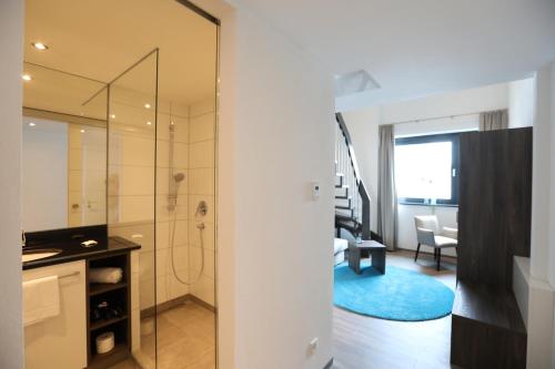 uma casa de banho com uma cabina de duche ao nível do chão e uma porta de vidro em 3G Hotel em Fulda