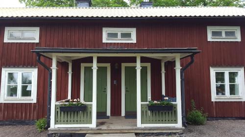 a red barn with two windows and a porch at Långshyttans Brukshotell in Långshyttan
