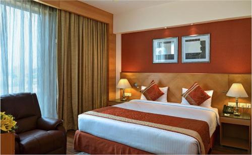 een hotelkamer met een groot bed en een stoel bij Savoy Suites Manesar in Gurgaon