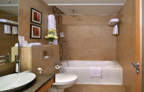 a bathroom with a tub and a toilet and a sink at Savoy Suites Manesar in Gurgaon