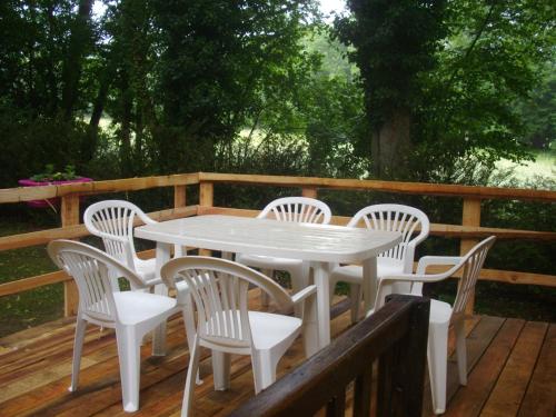 une table et des chaises blanches sur une terrasse en bois dans l'établissement Les chalets d'Alzen, à Alzen