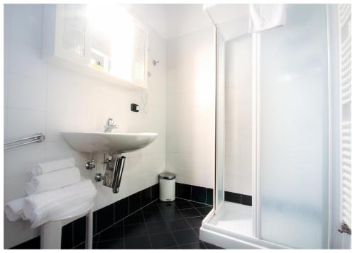 a white bathroom with a sink and a shower at Corte Dossello in Migliaro
