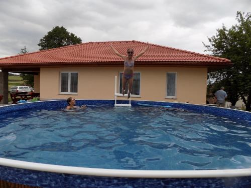 a woman standing on a chair in a swimming pool at Holiday House Adrelot in Heřmaničky