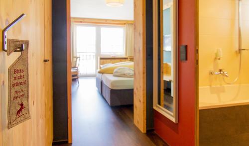 a room with a bed and a bathroom with a window at Wohlfühlhotel Hubertushof in Stuben am Arlberg