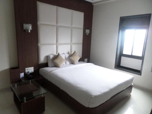 Hotel Raj Palace tesisinde bir odada yatak veya yataklar