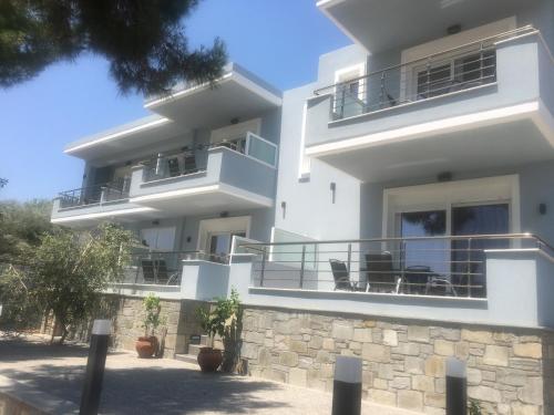 a large white building with balconies and tables at Isalos Suites in Néa Péramos