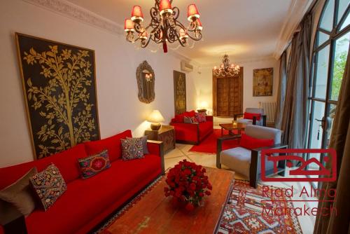 a living room with red couches and a chandelier at Riad Alma in Marrakech