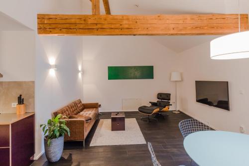 ein Wohnzimmer mit einem Sofa und einem TV in der Unterkunft GADEN Apartment - Hotel in Waging am See