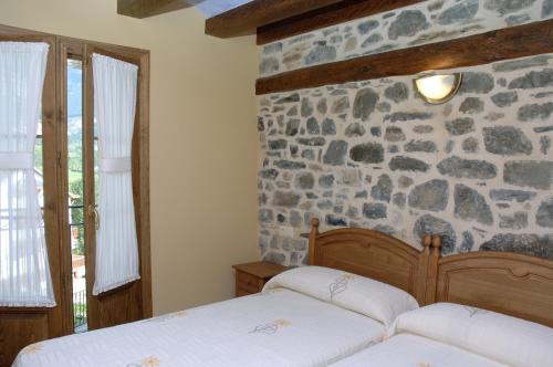 a bedroom with two beds and a stone wall at Casa el Parque Cajal in Torla