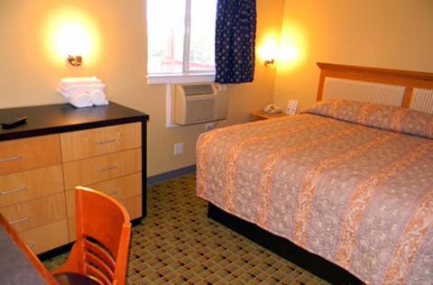 a hotel room with a bed and a dresser and a desk at Stay Inn & Suites - Stockbridge in Stockbridge