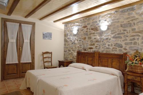 a bedroom with a bed and a stone wall at Apartamento el Hogar Casa Cajal in Torla-Ordesa