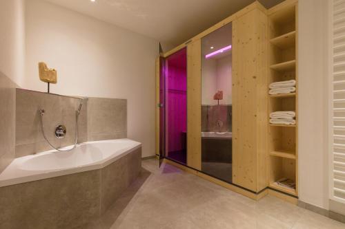 ein Bad mit einer Badewanne und einer ebenerdigen Dusche in der Unterkunft GADEN Apartment - Hotel in Waging am See