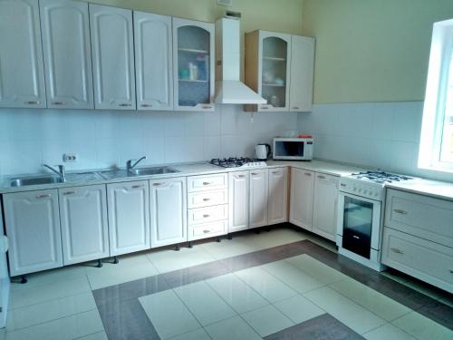 a white kitchen with white cabinets and appliances at Lime Guest House in Adler