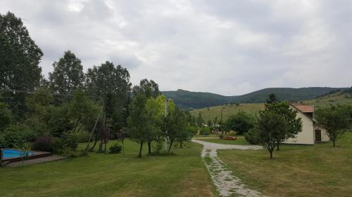 a path in a field with trees and a house at Panzió-Kemping Bekölce in Bekölce
