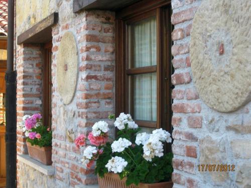 a brick building with flowers in front of a window at Hotel Rural El Espino in Cangas de Onís