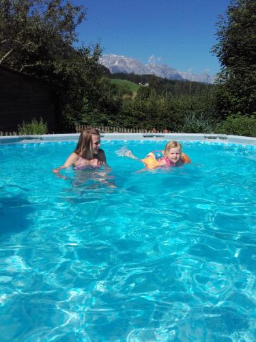 two young girls swimming in a swimming pool at Ferienhaus Regina in Werfenweng