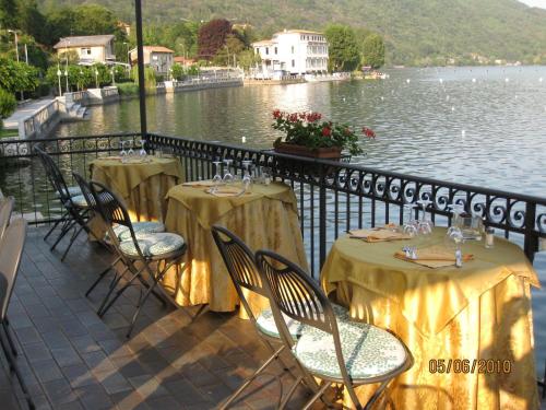 two tables and chairs with wine glasses and a body of water at Hotel Due Palme in Mergozzo