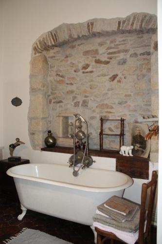 une baignoire dans une pièce avec un mur en pierre dans l'établissement la maison des chartreux, à Brives-Charensac