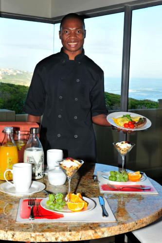 a man holding a plate of food on a table at Marine 5 Boutique Hotel in Gansbaai