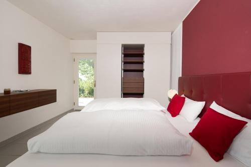 1 dormitorio con 2 camas blancas y almohadas rojas en Seeblick Appartement Henle en Lochau