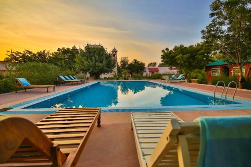 a large swimming pool with two chairs next to it at The Shergarh in Khilchipur