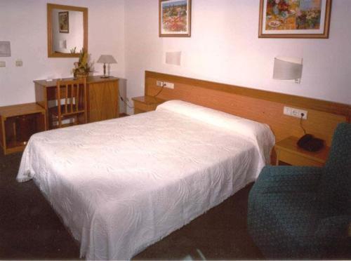 - une chambre avec un lit blanc et une chaise bleue dans l'établissement Hotel San Vicente, à Saint-Jacques-de-Compostelle